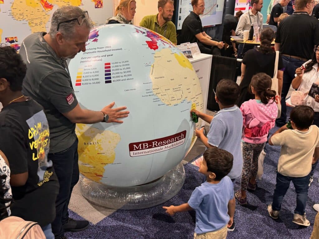 Das Foto zeigt Kinder, die Spaß mit dem MBI-Kaufkraftglobus am MBI-Stand auf der Esri UC 2024 in San Diego haben